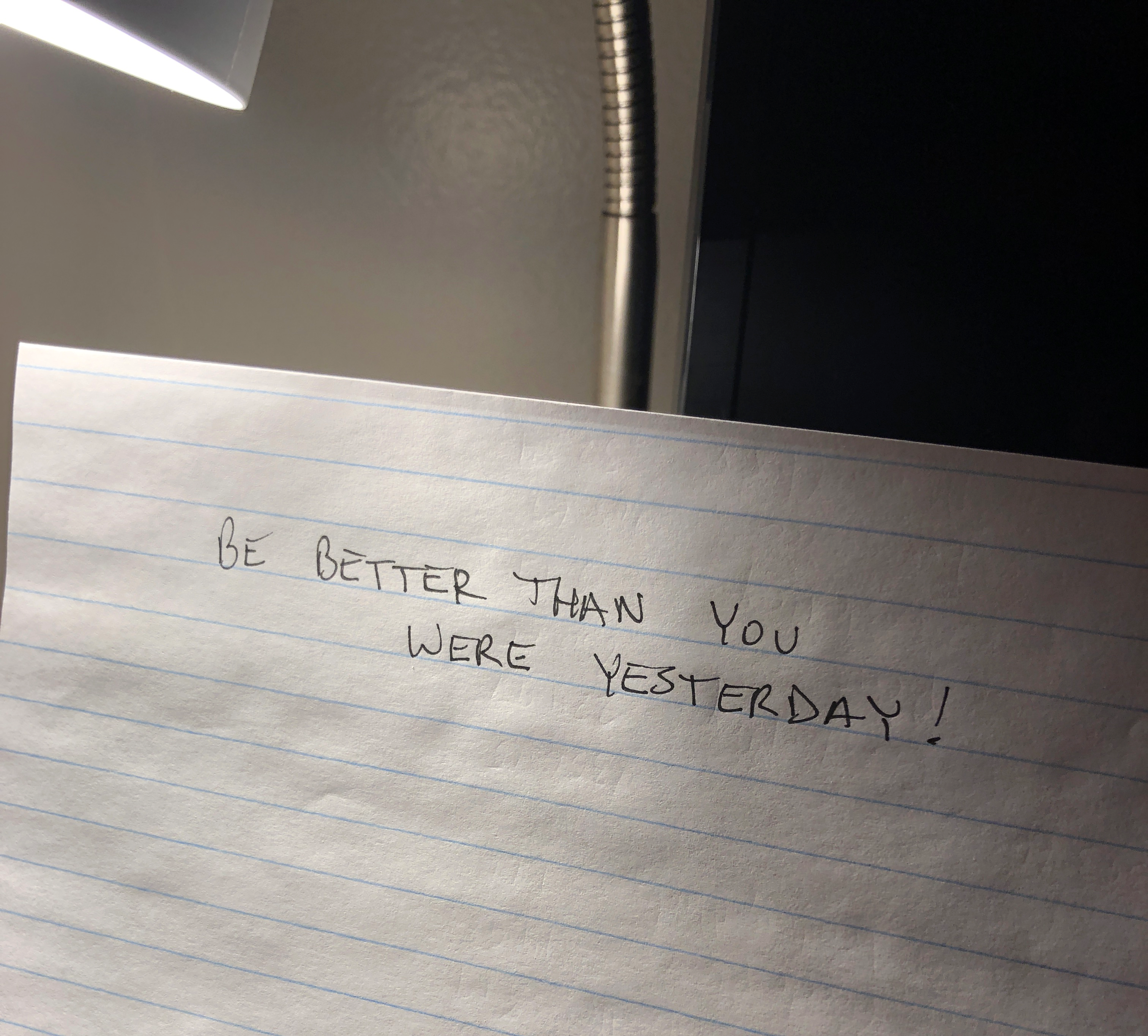 A piece of paper on my side table that reads, 'Be better than you were yesterday'.